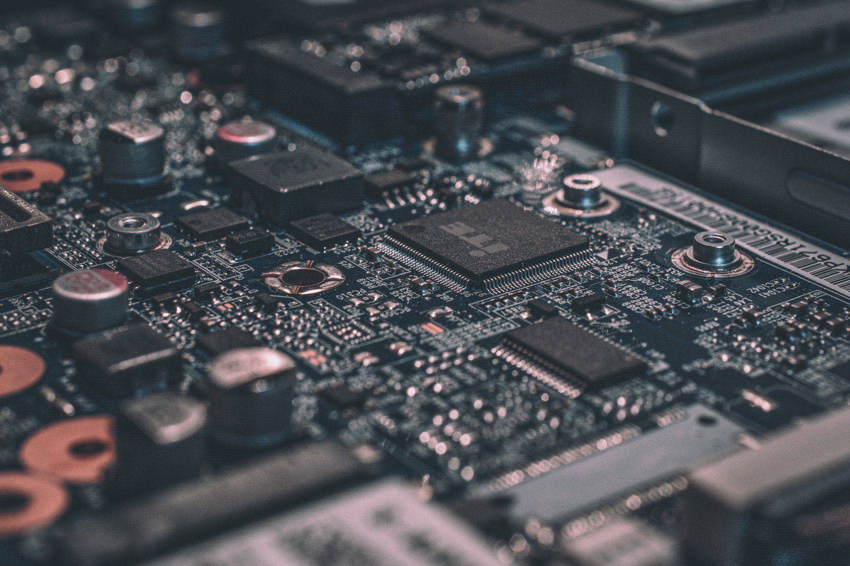 Close-up of a green circuit board lit in blue, its traces and components filling the frame.