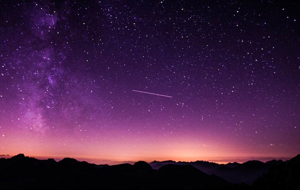 Green and purple aurora light rippling across a star-filled night sky.
