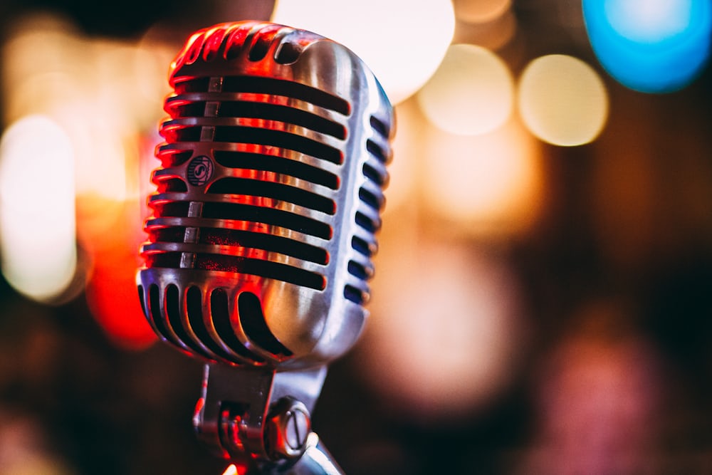 A vintage chrome microphone in close-up against a warm blurred background.